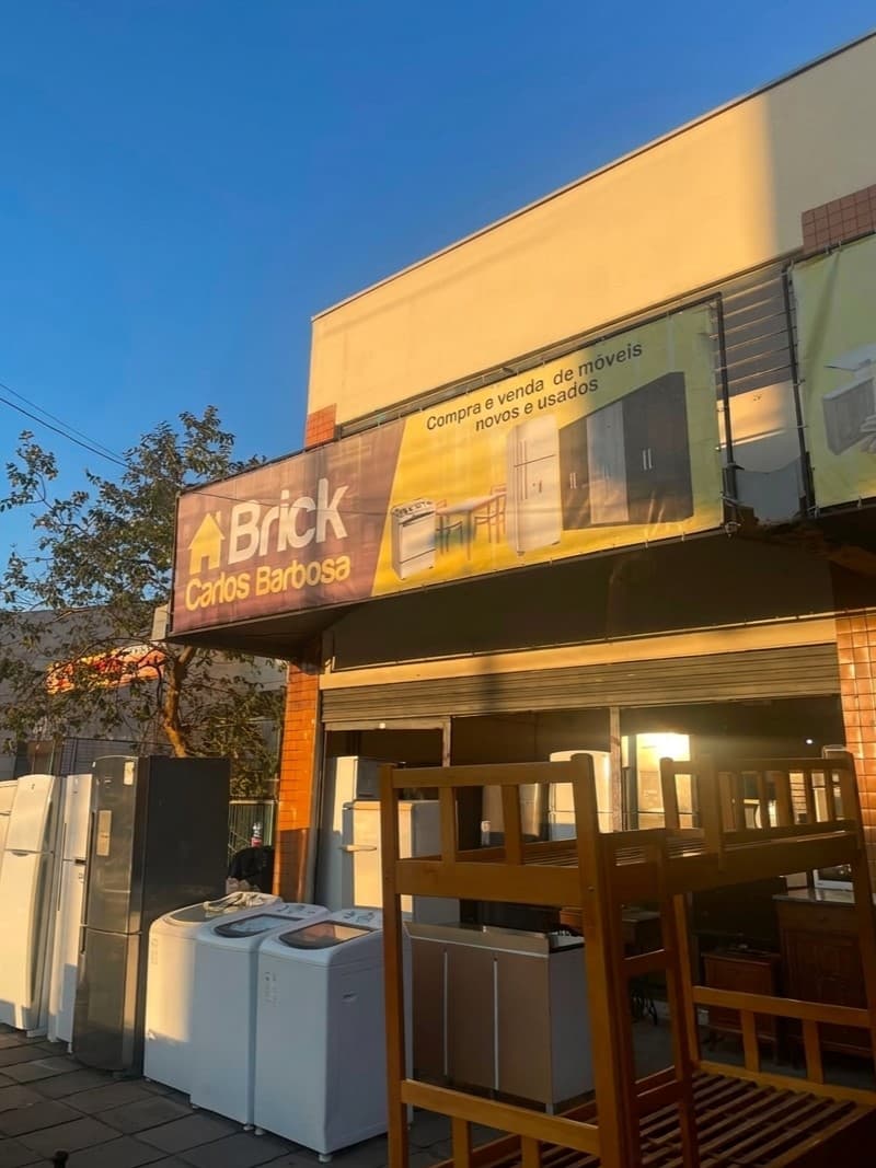 Fachada da loja Brick Carlos Barbosa, com a placa amarela e azul e móveis e eletrodomésticos expostos na calçada